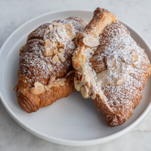 Our almond croissant is a double-baked croissant that consists of our classic butter croissant that is filled and topped with house-made almond paste and sliced almonds. Once baked, we finish the croissants with a sprinkling of powdered sugar. Baked fresh daily.