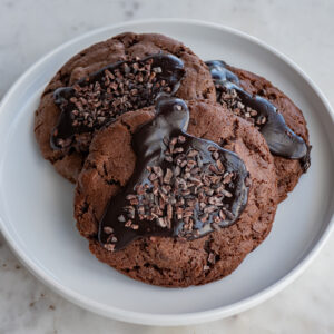 If you love chocolate, then our double chocolate cookies are perfect for you. These cookies consist of a dark chocolate cookie dough with Belgian dark chocolate chips mixed throughout. Once baked, we pipe chocolate caramel into and on top of the cookies while still warm. To finish, we sprinkle cacao nibs on top.